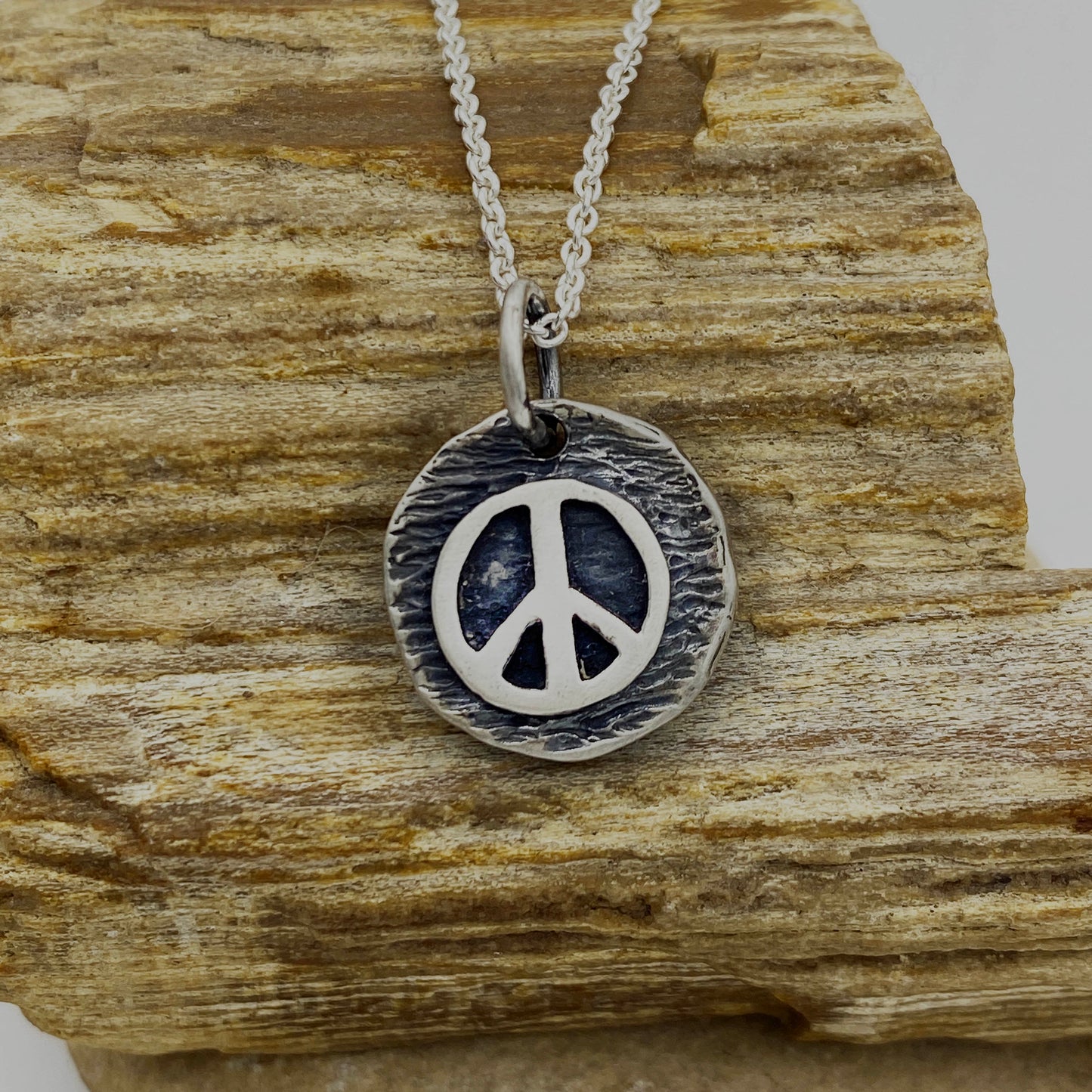 Sterling Silver Peace symbol on top of a Round, flat disc representing the World Pendant with a 22" Adjustable Cable Chain